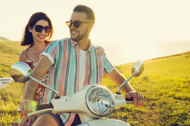 Couple of young friends having fun and smiling on a motorcycle