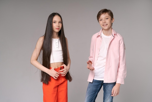 Couple young funny and happy guy and girl posing in studio studio on gray