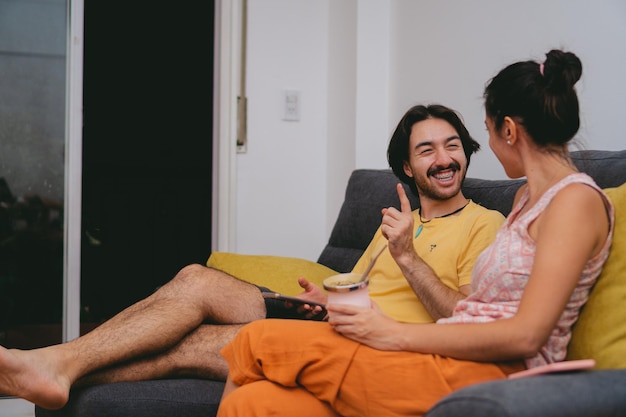 Couple of young Latin friends happily gossiping in their living room while sharing a mate Copy space