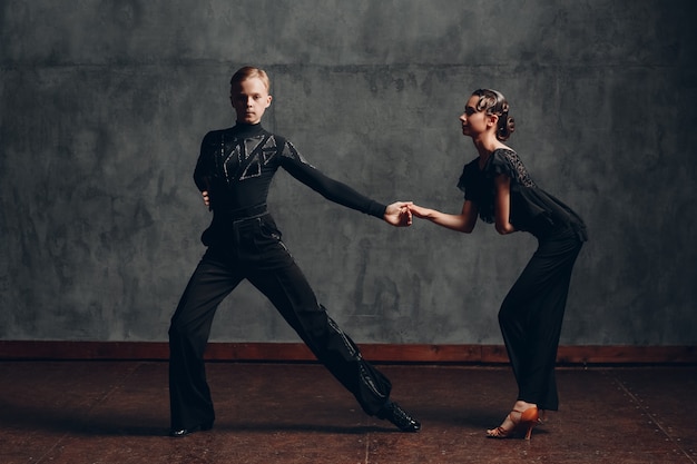 Couple young man and woman in black dress dancing in ballroom dance rumba.