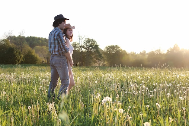 Couple of young people walking in the sunset spring evening in field