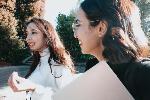 Couple of young woman student of college walking through the
campus. they walks trough university campus and laughing after
meeting again at the university. study together and learning
concept. trendy