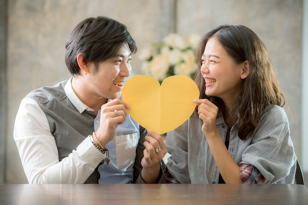 Couples of asian man and woman holding heart shape paper cut with happiness emotion ,people love conceptual