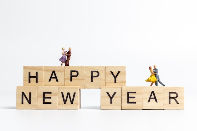 Couples dancing on Happy new year lettering wooden block 