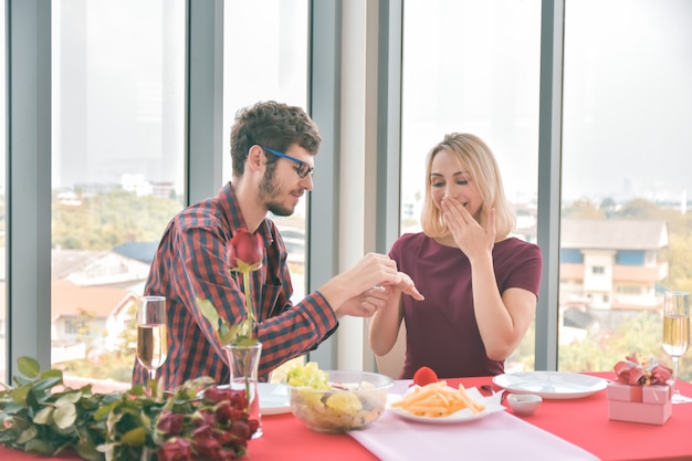 カップルが手をつないで、テーブルで結婚を提案する