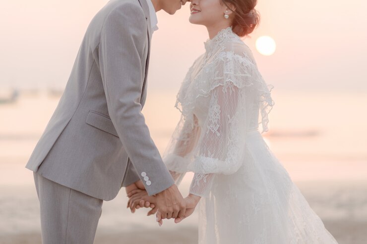 Photo カップルが手を繋いでいると海沿いのビーチでキスします。愛の概念