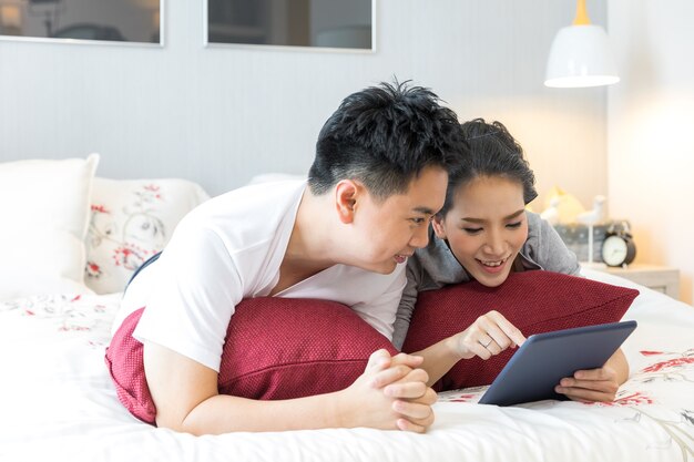 Couples lying using tablet on bed