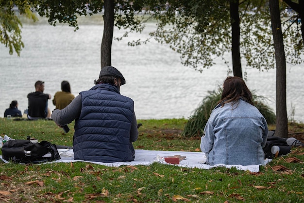 Couples relaxing on the grass in a park by the river and enjoying food The concept of freedom and relaxation