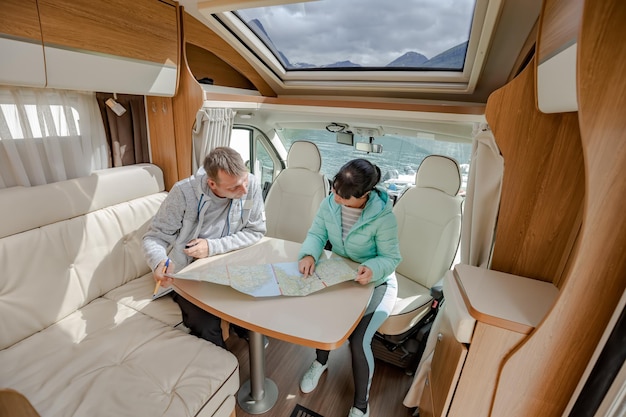 Couples in RV Camper looking at the local map for the trip. Family vacation travel, holiday trip in motorhome, Caravan car Vacation.