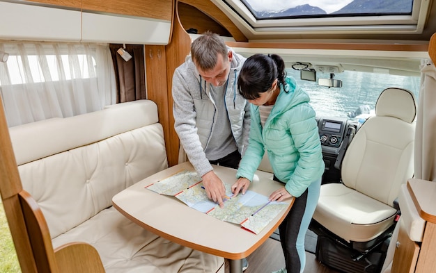 Couples in RV Camper looking at the local map for the trip. Family vacation travel, holiday trip in motorhome, Caravan car Vacation.