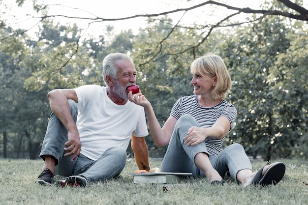 Photo couples senior give apples to each other together happily.