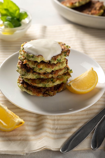 Courgette beignets of vegetarische courgette pannenkoeken geserveerd met yoghurtsaus en citroen