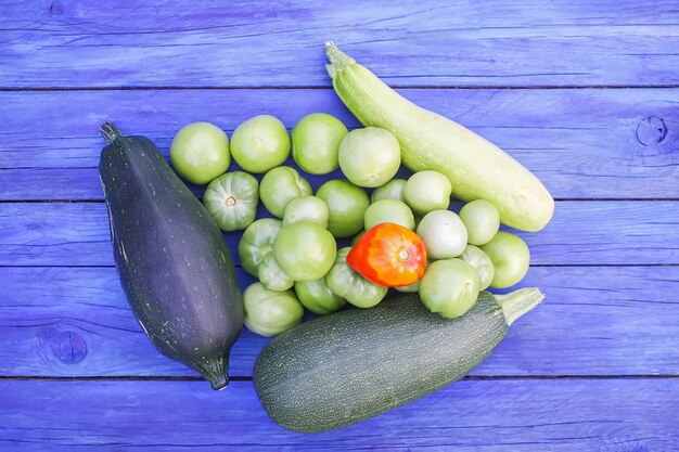 Courgette en onrijpe tomaten. Verse rauwe biologische groenten op houten planken buiten.