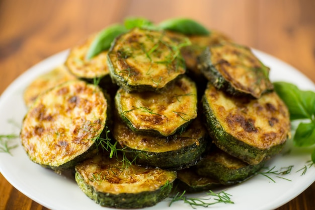 Courgette gebakken in cirkels met specerijen en kruiden in een bord op een houten tafel