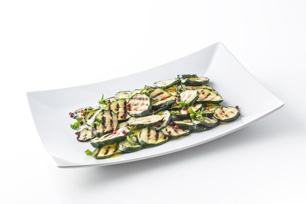 Courgette. Gegrilde courgette met rood kruid op witte plaat.