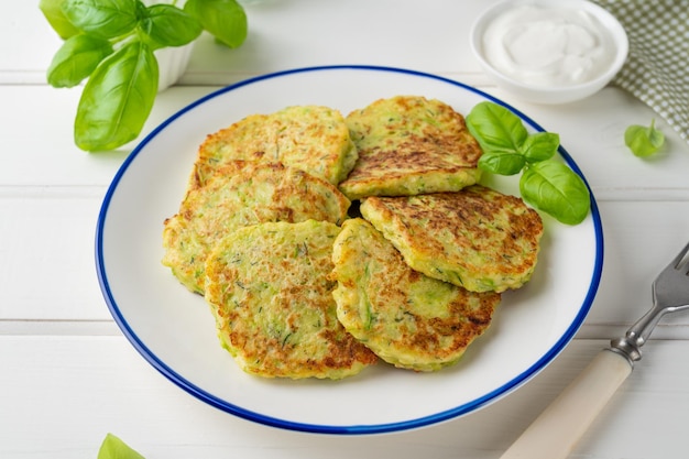 Courgettebeignets met kaas knoflook en kruiden Vegetarische courgettepannenkoekjes geserveerd met basilicum