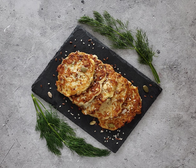 Courgettebeignets met takjes dille op lichte achtergrond, bovenaanzicht, plat gelegd.