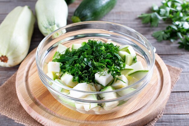 Courgetteblokjes met kruiden in een glazen kom op een houten tafel