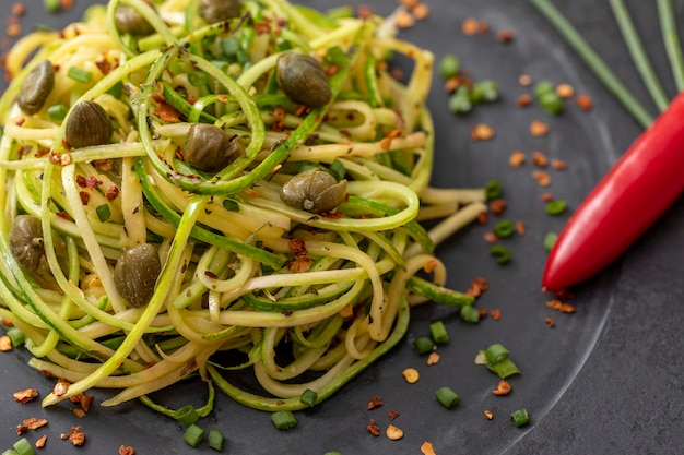 Courgettespaghetti met gedroogde pepperoni peper en kappertjes.