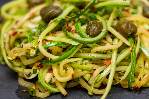 Courgettespaghetti met gedroogde pepperoni peper en kappertjes.