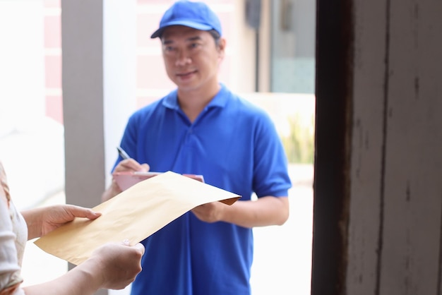 Courier in blue uniform giving envelope to customer