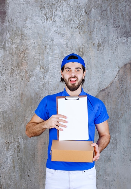 Photo courier in blue uniform holding a takeaway box and asking for a signature