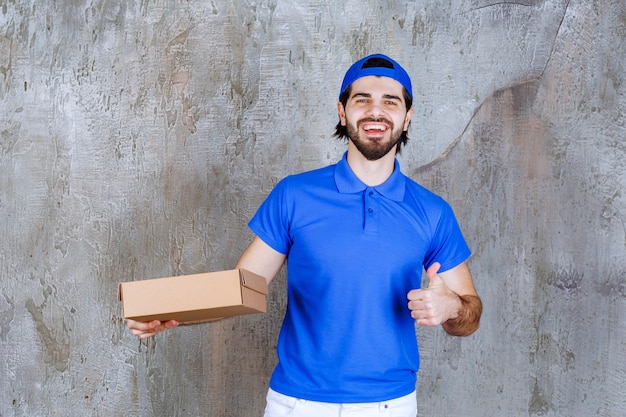 Courier in blue uniform holding a takeaway box and showing positive hand sign. 