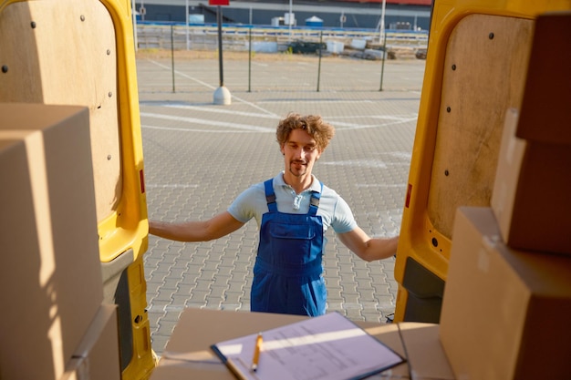 Foto corriere che chiude le porte del furgone di consegna con una pila di scatole di cartone dopo la spedizione che ispeziona prima del trasporto