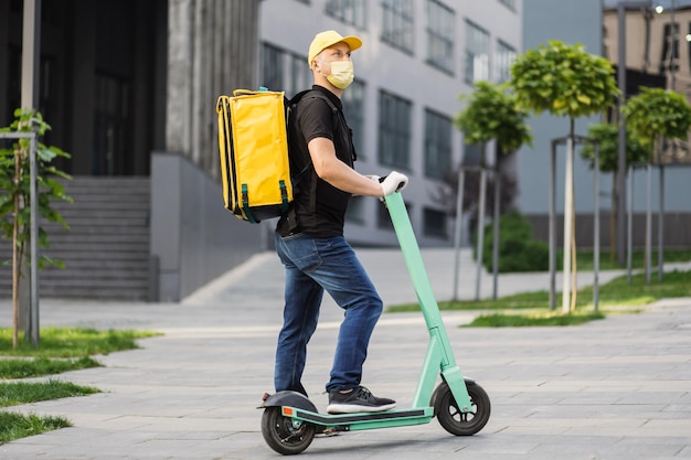 Courier deliver food on electric scooter wearing yellow facial protective mask