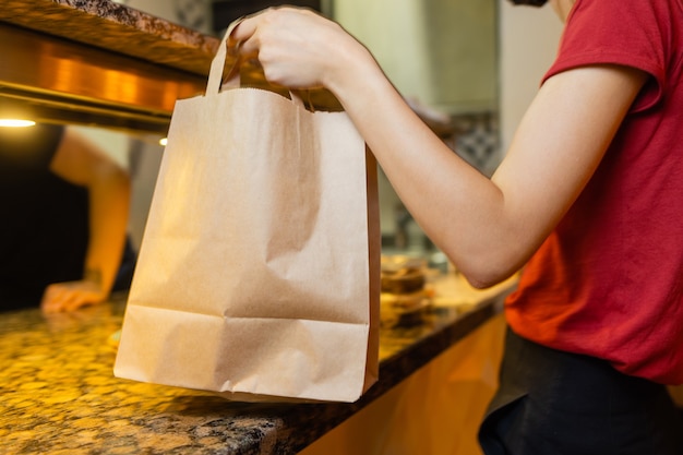 Courier delivery food service at home. Woman courier delivered the order no name bag with food.