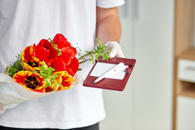 Photo courier, delivery man in medical latex gloves safely delivers online purchases a bouquet of flower