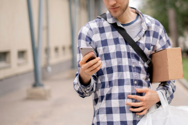 Courier die een telefoon gebruikt om het adrespad te zoeken om pakketten te leveren