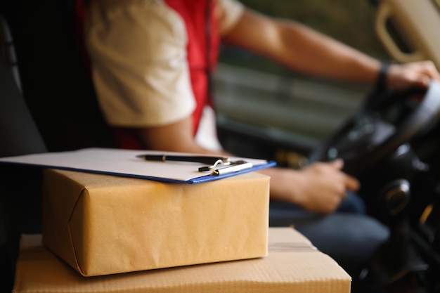 Photo courier driving delivery van focus on parcels and clipboard