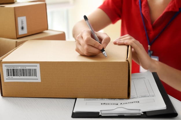 Photo courier hands writing on cardboard box at table