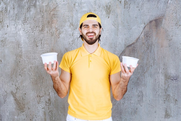 プラスチック製のコップを保持している黄色の制服を着た宅配便