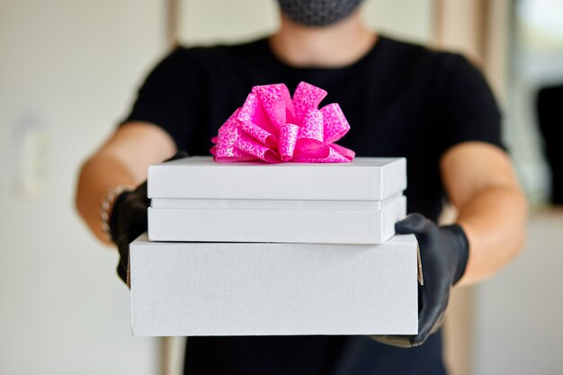 Courier man contactless delivery presents, gift box during a coronavirus epidemic.