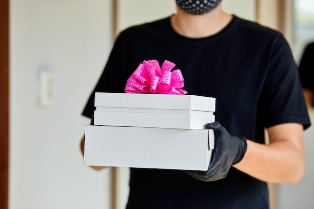 Courier man contactless delivery presents, gift box during a coronavirus epidemic.