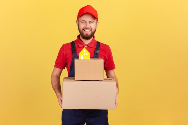 Courier man holding cardboard boxes with paper house on top movement company