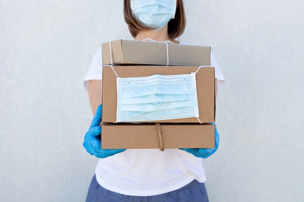 Courier in medical mask and gloves is holding boxes