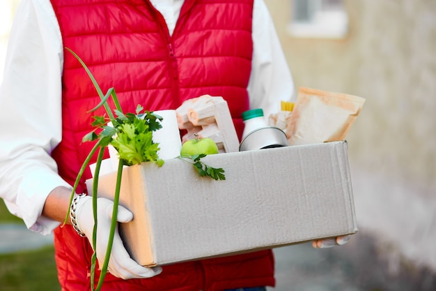 Photo courier in protective mask and medical gloves delivers food box