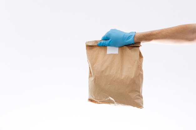 Courier in protective mask and medical gloves delivers takeaway food. Delivery service under quarantine, disease outbreak, coronavirus covid-19 pandemic conditions.