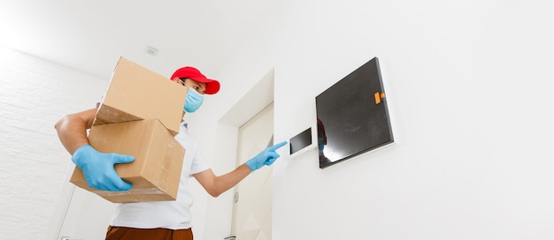 Courier in protective mask and medical gloves delivers takeaway food. Delivery service under quarantine, disease outbreak, coronavirus covid-19 pandemic conditions.