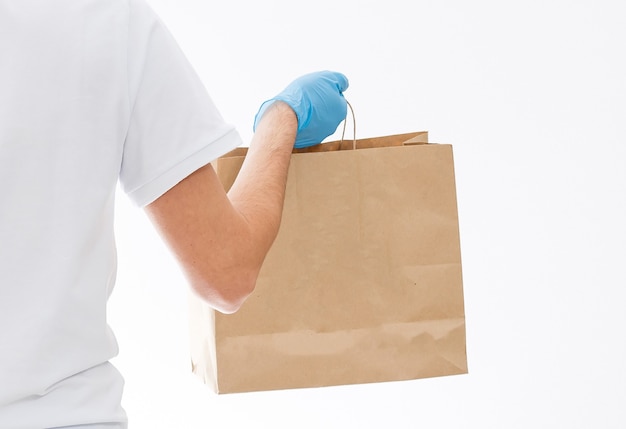 Courier in protective mask and medical gloves delivers takeaway food. Delivery service under quarantine, disease outbreak, coronavirus covid-19 pandemic conditions.