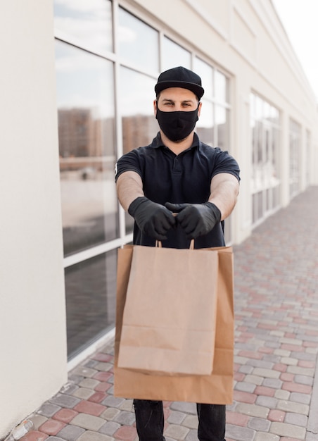 Courier in protective mask and medical gloves delivers takeaway food