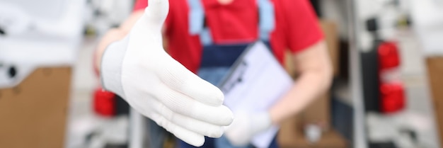 A courier in a red uniform holds out his hand in a white glove