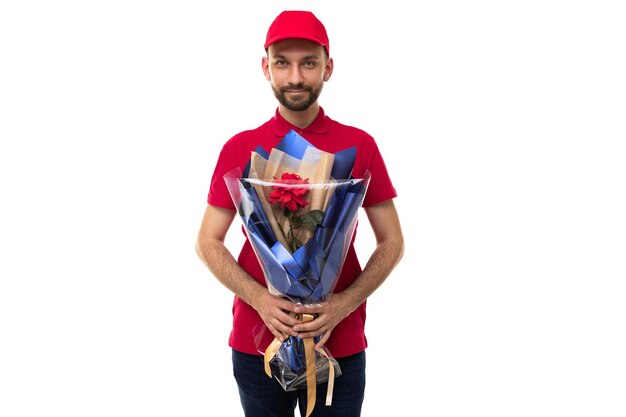 Courier in a red uniform on a white background delivers a bouquet of flowers