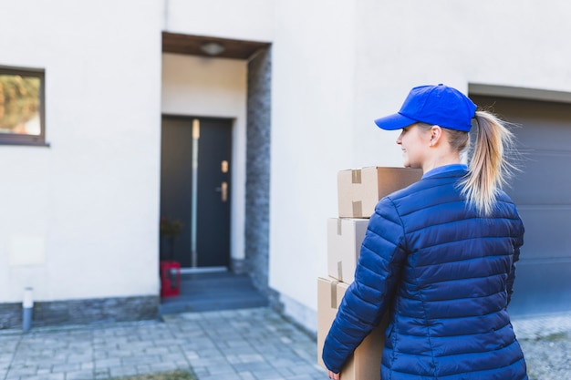 Courier with boxes walking to house