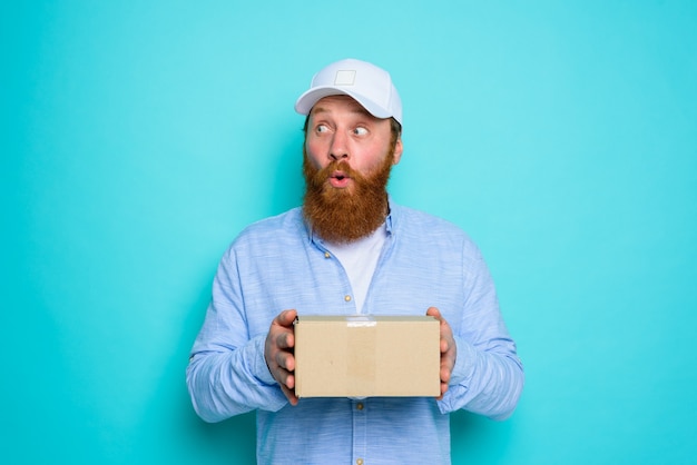 Courier with carton box in hand is surprised about something