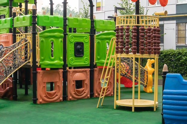 A courtyard of high-rise buildings with a new modern colorful and large playground on a rainy summer day without people. Empty outdoor playground. A place for children's games and sports.