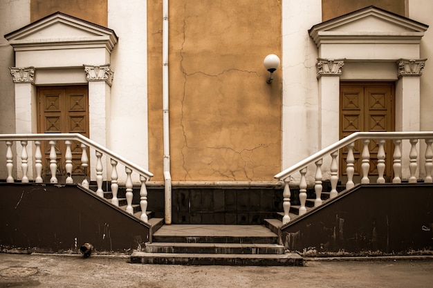 Courtyard of an old architectural building, two massive doors with White stone stairs on the sides